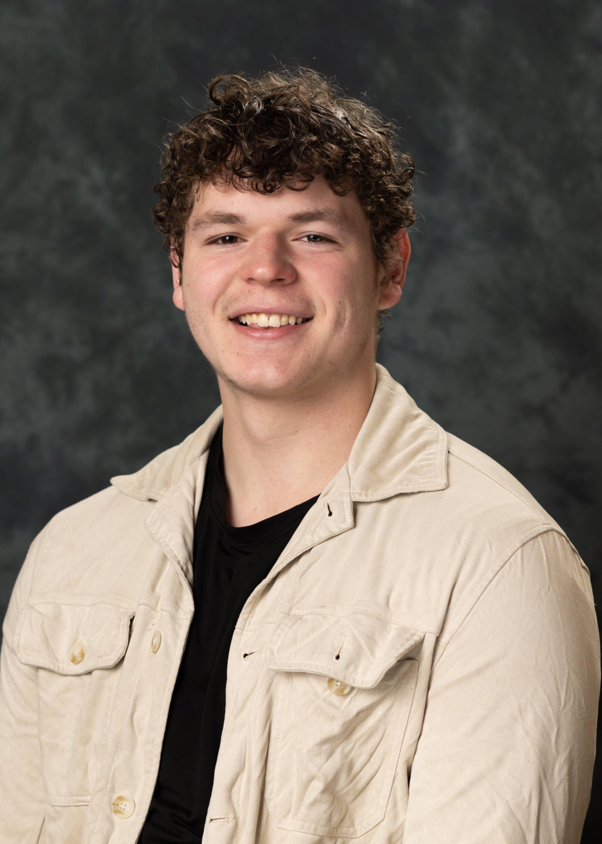 Connor McKay smiling in a cream white jacket